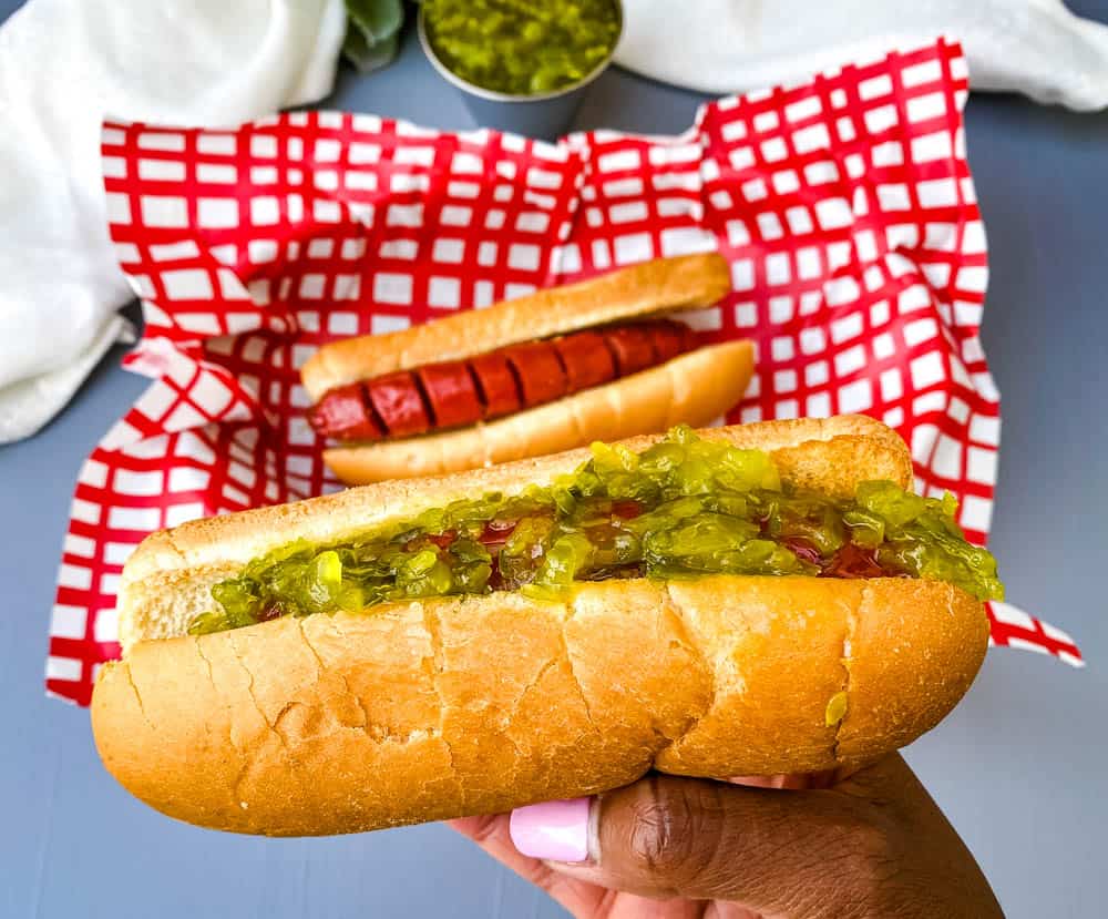 person holding air fryer hot dog in a bun with relish
