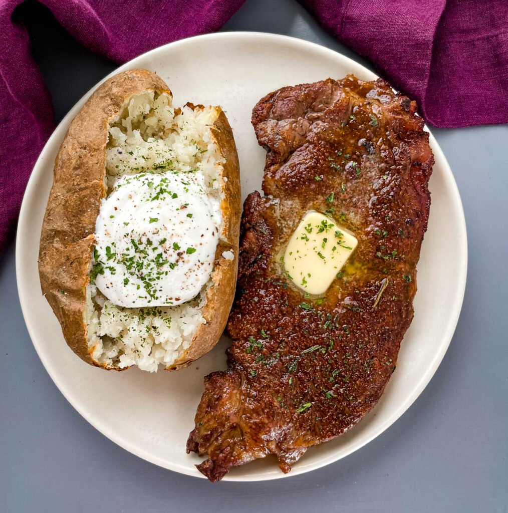 air fryer steak on a plate with butter with a baked potato