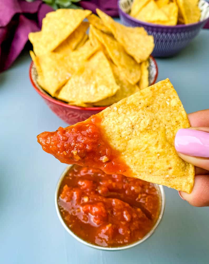 person holding air fryer tortilla chip with salsa