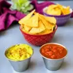 air fryer tortilla chips in a red bowl with guacamole and salsa