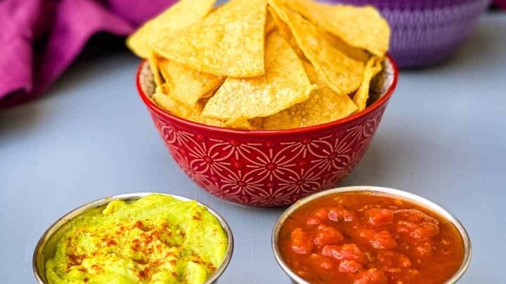 air fryer tortilla chips in a red bowl with guacamole and salsa