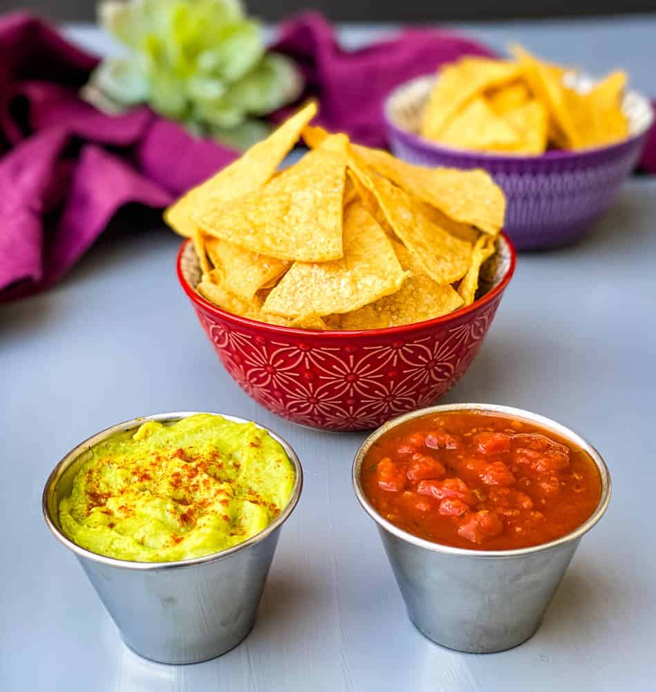 air fryer tortilla chips in a red bowl with guacamole and salsa