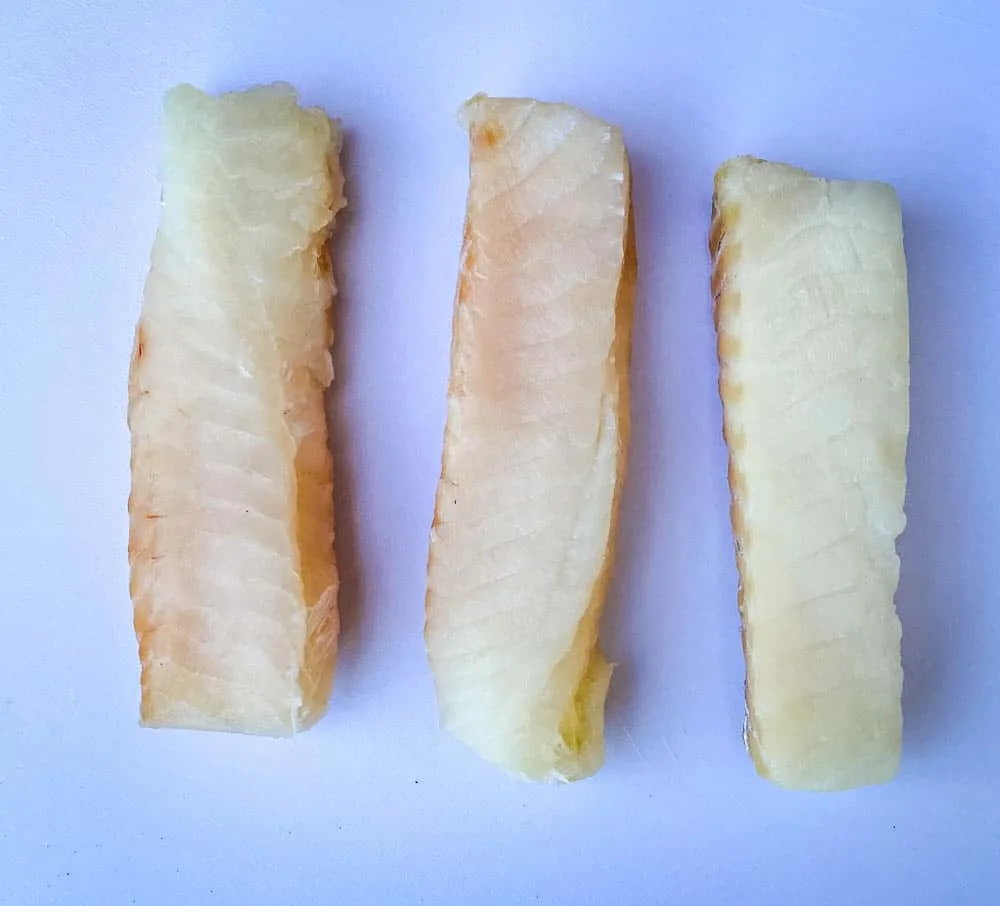 fresh cod fillets on a cutting board