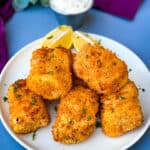 air fryer fish sticks on a white plate with tarter sauce and lemons