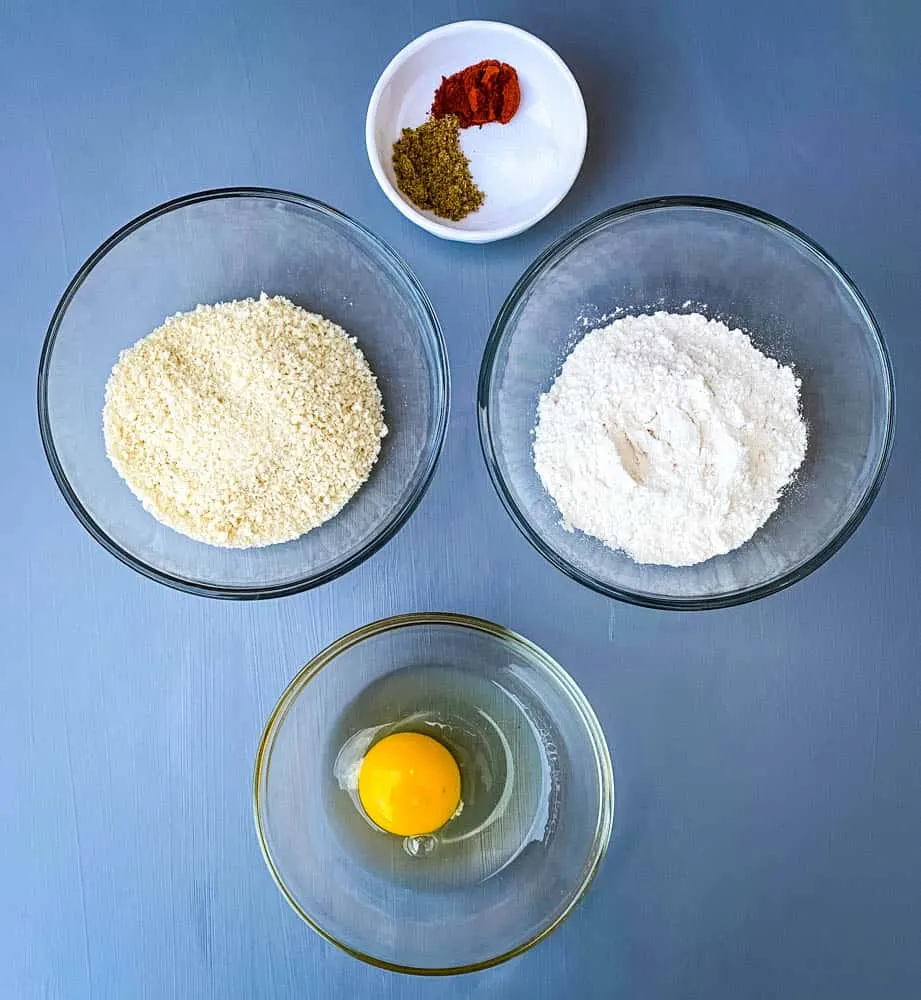 flour, breadcrumbs, an egg, and seasoning in separate bowls