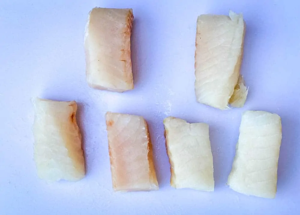 fresh cod fillets on a cutting board