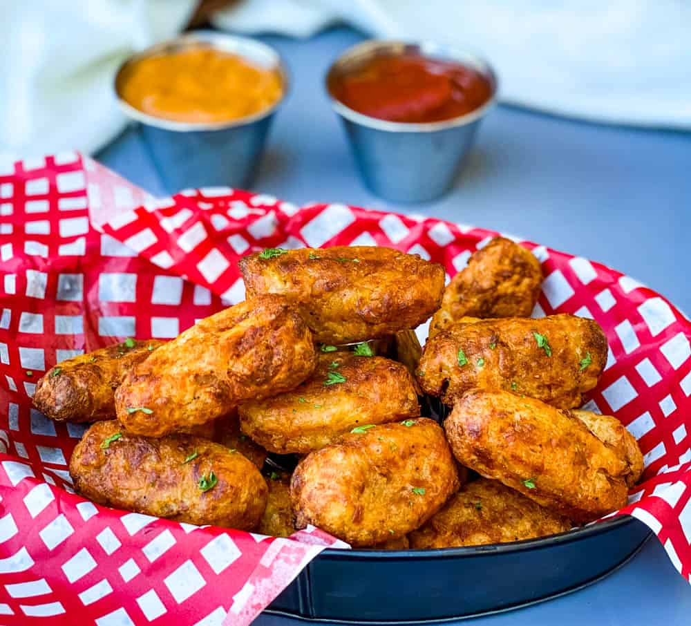 air fryer tater tots in a red and white basket with ketchup and chipotle mayo