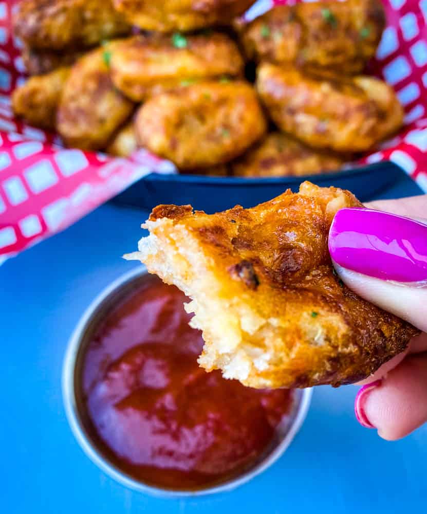 person holding an air fryer tater tot with a bite taken out