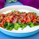 BLT dip with lettuce, bacon, and tomatoes in a blue serving dish