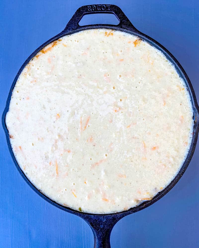 cornbread batter on top of tamale pie in a cast iron skillet 