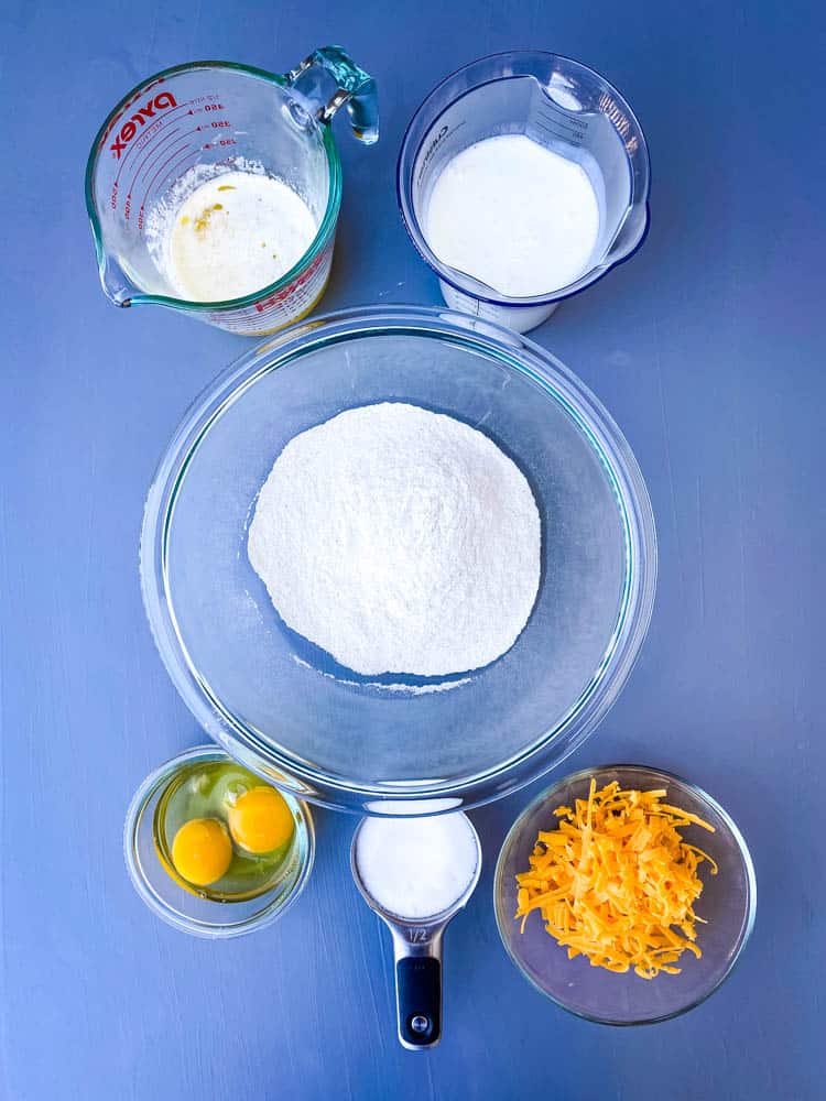 butter, cornmeal, eggs, sweetener, buttermilk, and shredded cheese in separate bowls for homemade cornbread