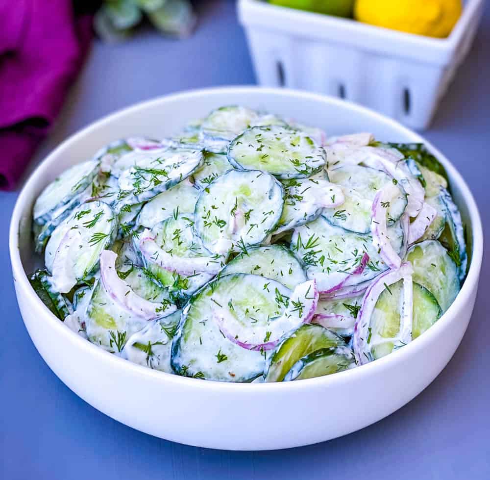 creamy cucumber salad with red onions in a white bowl
