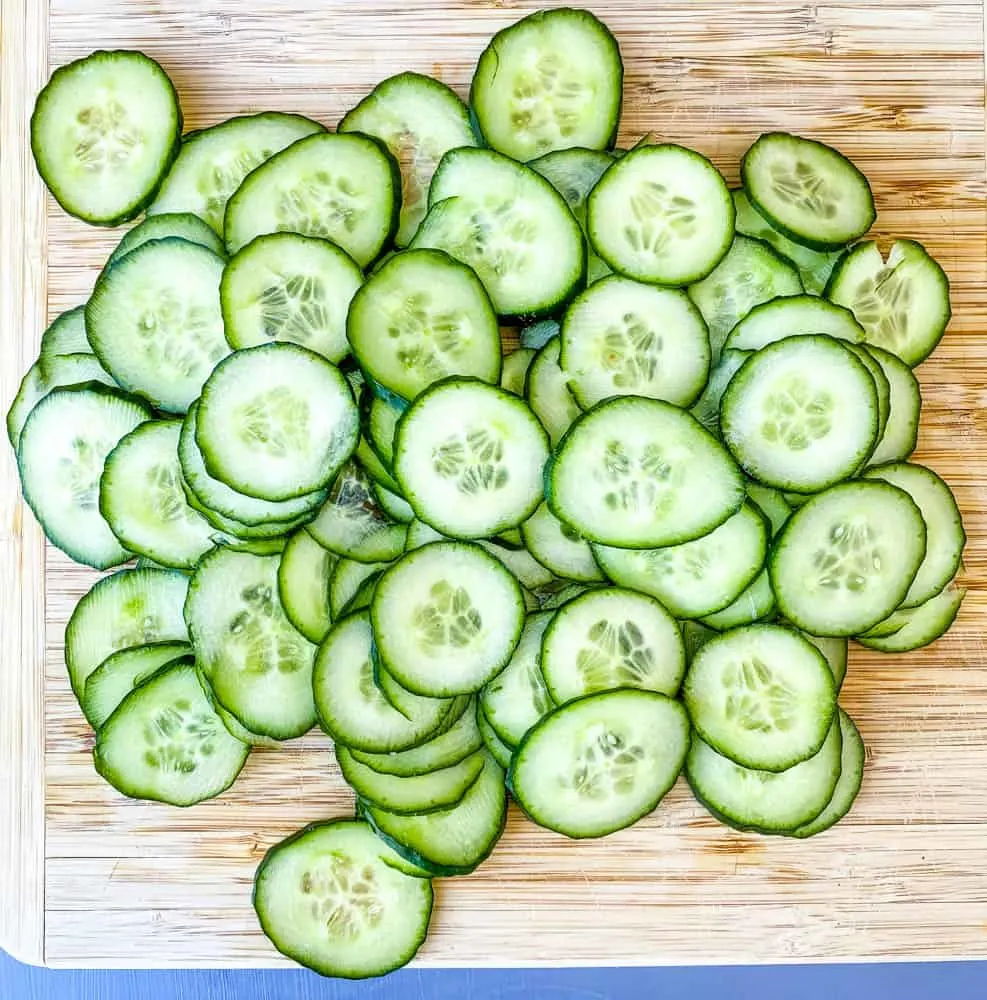 thinly sliced cucumbers on a bamboo cutting board