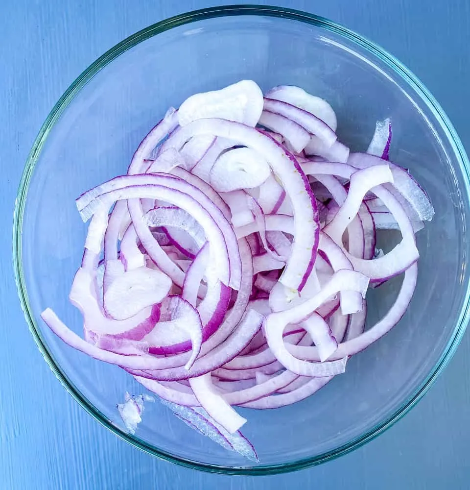 thinly sliced onions in a glass bowl