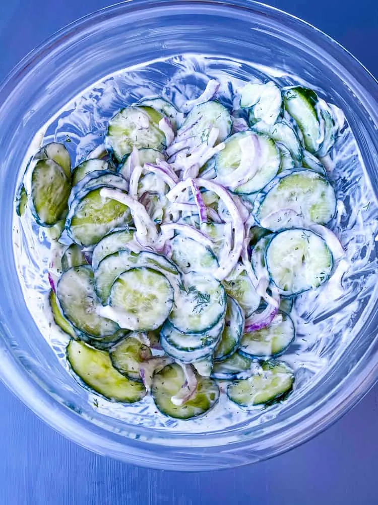 creamy cucumber salad with red onions in a glass bowl