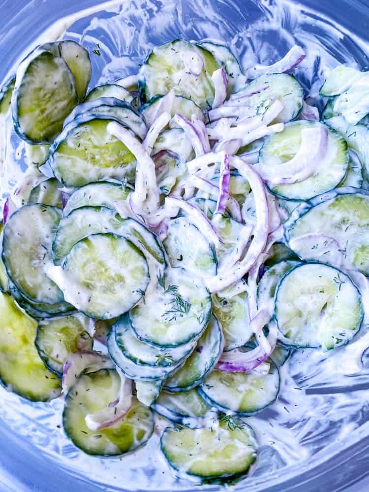 creamy cucumber salad with red onions in a glass bowl