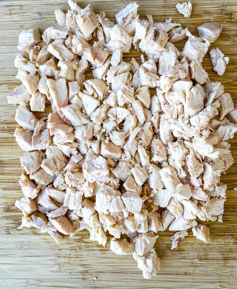 cooked and cubed chicken breasts on a bamboo cutting board