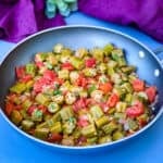 okra and tomatoes in a skillet with a purple napkin