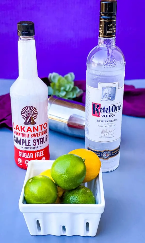 simple syrup, vodka, and fresh limes on a flat surface