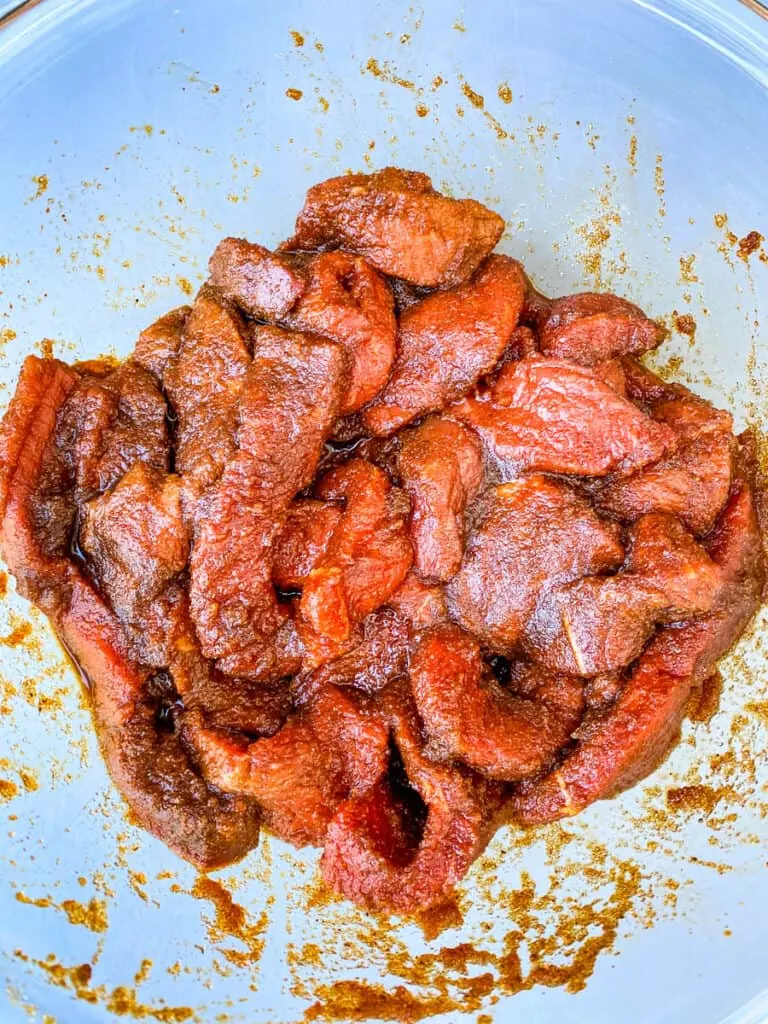 raw marinated beef in a glass bowl for air fryer beef jerky
