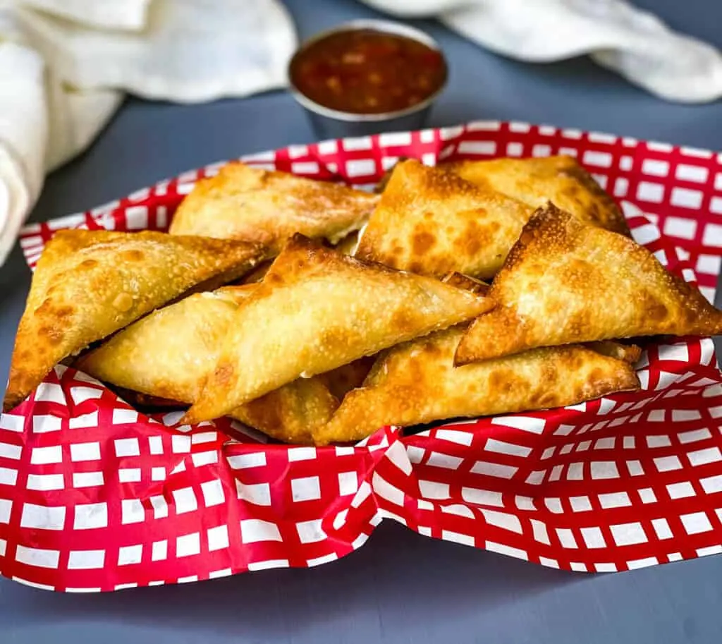 air fryer wontons in a basket with red wrapping