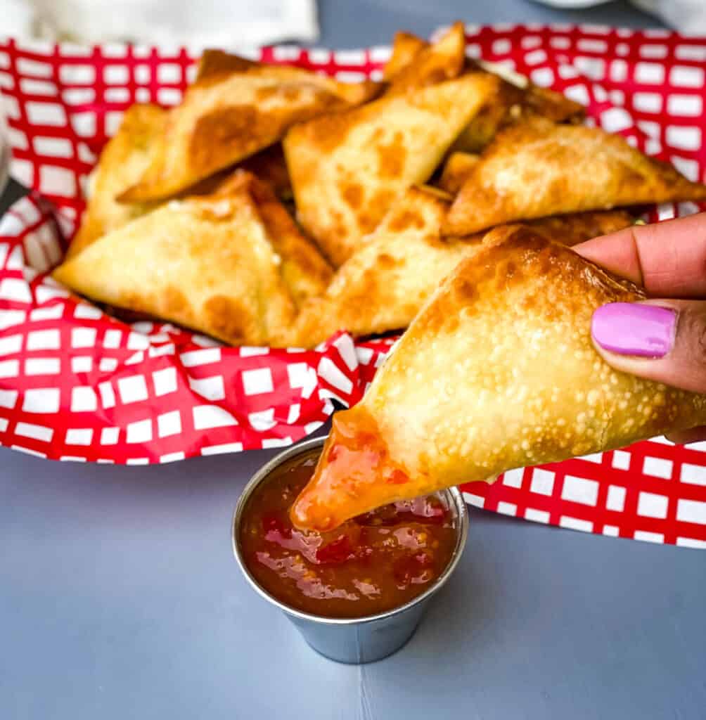 person holding air fryer wonton with dipping sauce