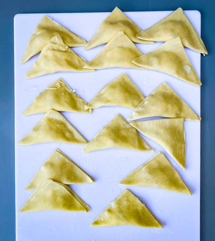 wontons folder in a triangle on a white cutting board