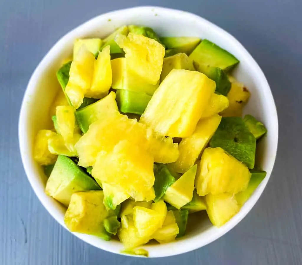 fresh cut pineapple and avocado in a white bowl