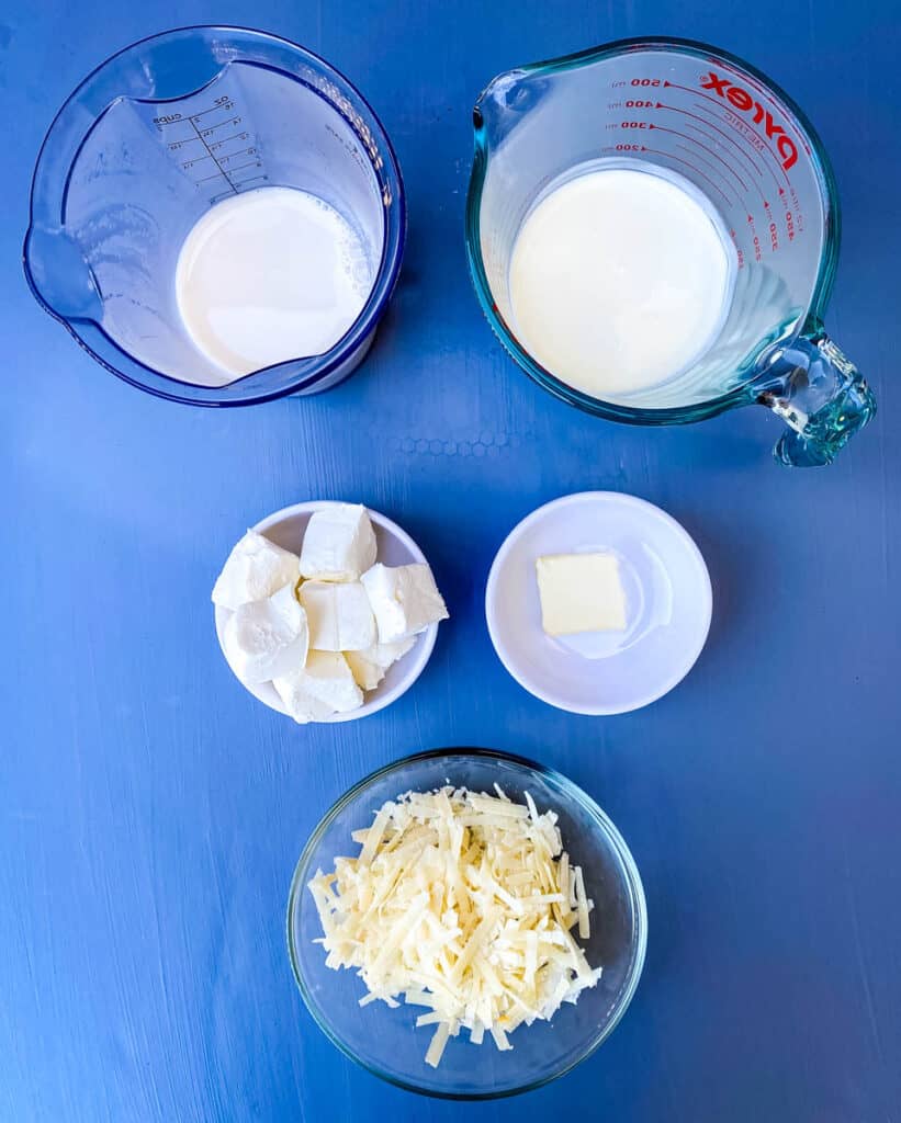 heavy cream, almond milk, cream cheese, butter, and Parmesan cheese in separate bowls