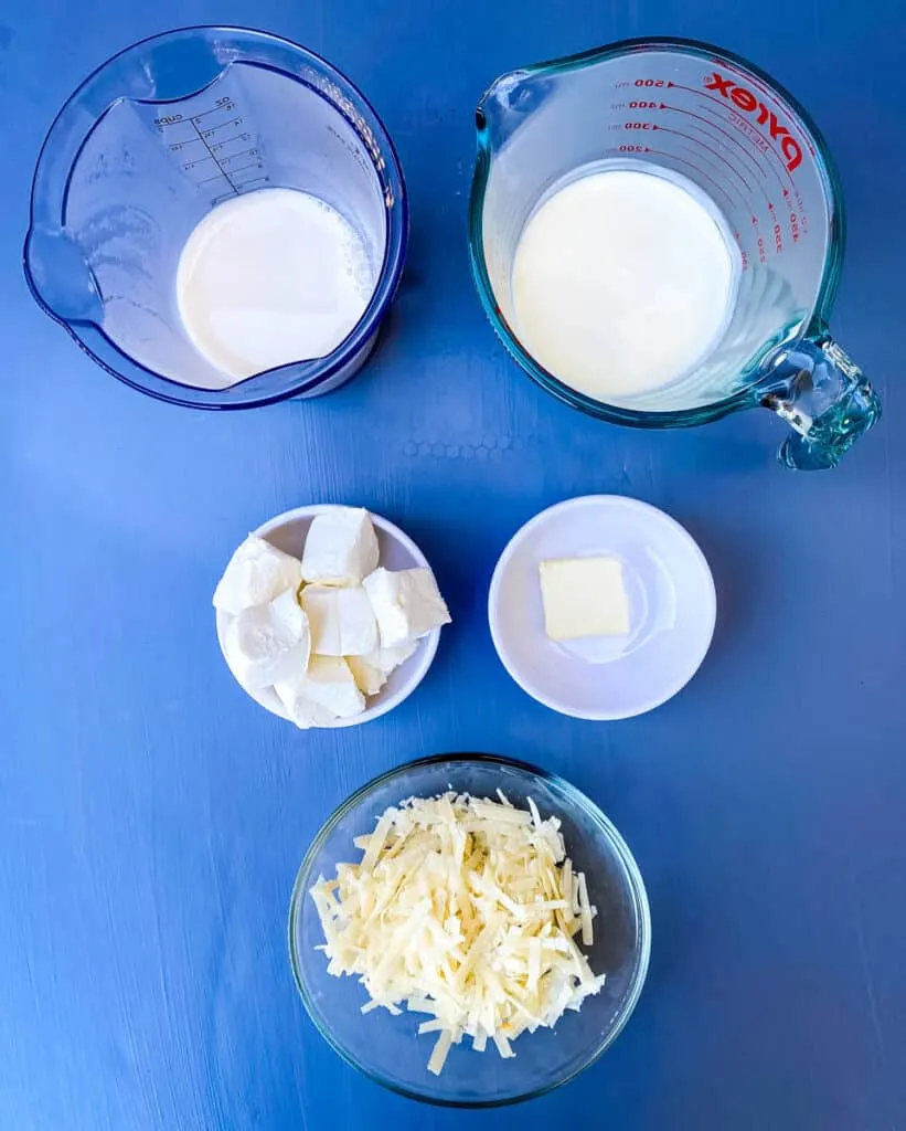heavy cream, almond milk, cream cheese, butter, and Parmesan cheese in separate bowls