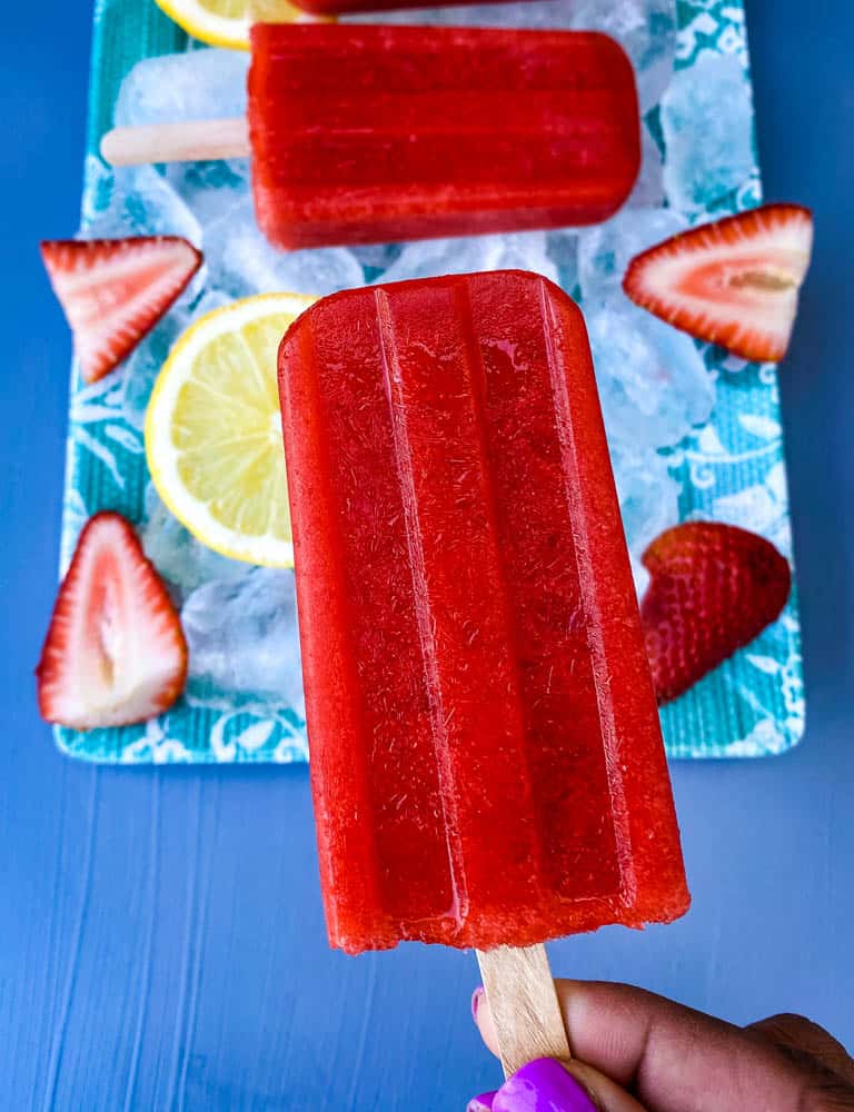 osoba trzymająca bezcukrowy truskawkowo-cytrynowy popsicle