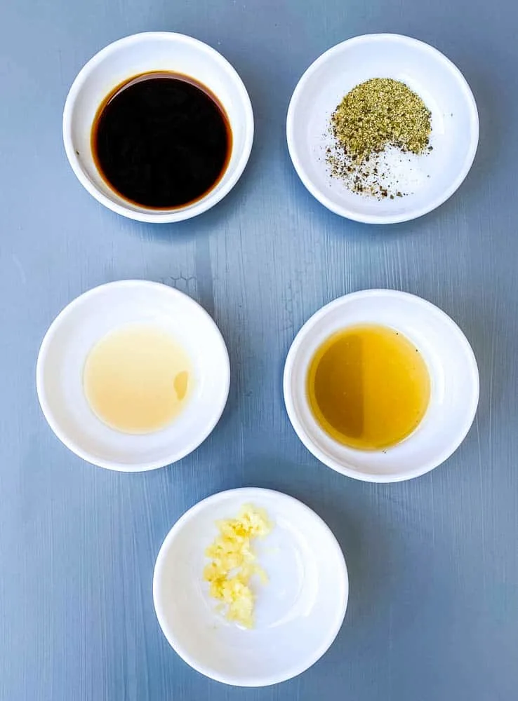 soy sauce, fish sauce, garlic, and seasoning in separate small white bowls