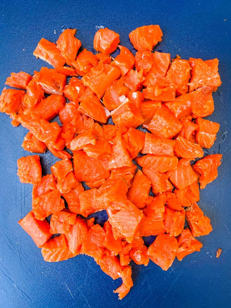 wild caught salmon cut into chunks on a cutting board