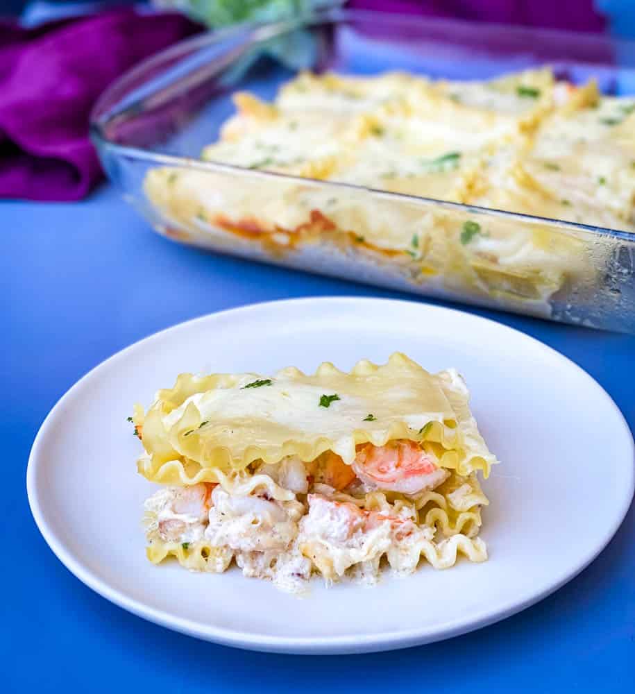 a slice of seafood lasagna on a plate with a baking pan of lasagna