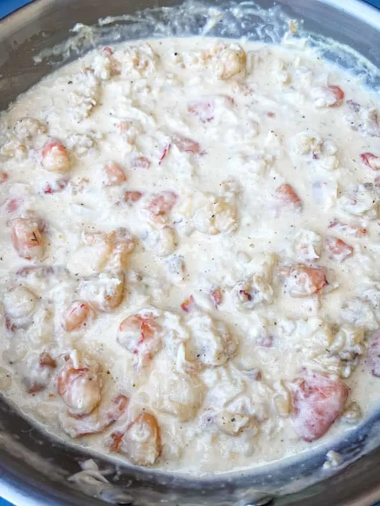 cooked seafood with a white cream sauce in a pan