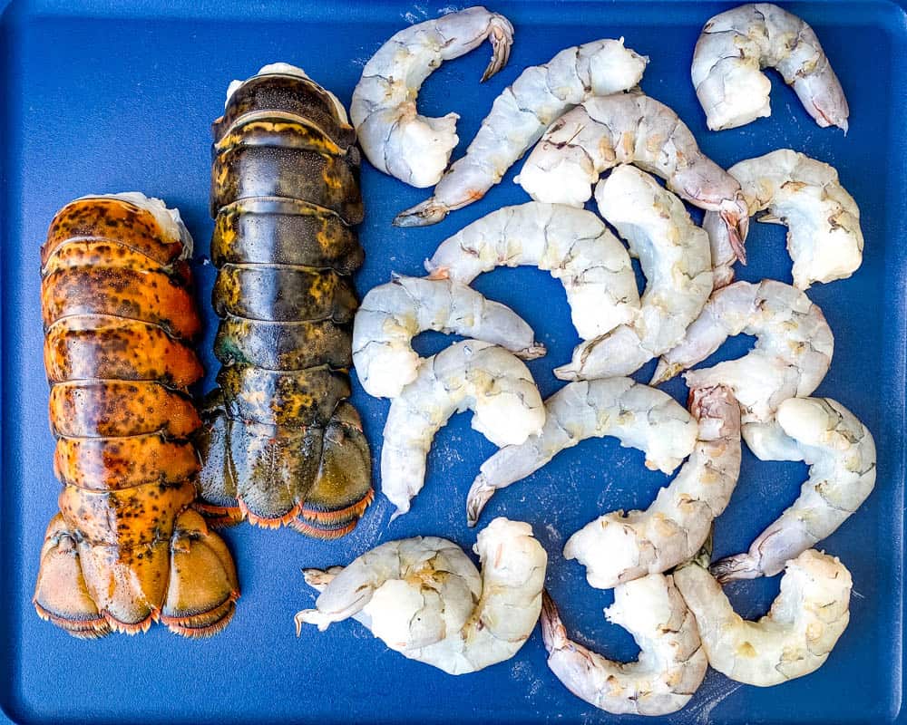 raw lobster tails and raw shrimp on a cutting board