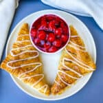 air fryer turnovers on a white plate with a bowl of cherries