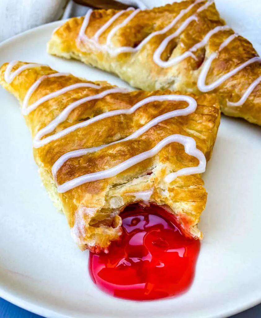 an air fryer turnover on a plate oozing with cherry filling