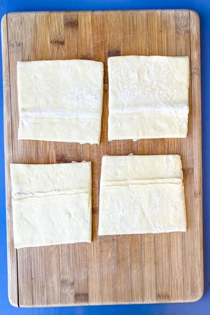 4 sheets of puff pastry on a bamboo cutting board