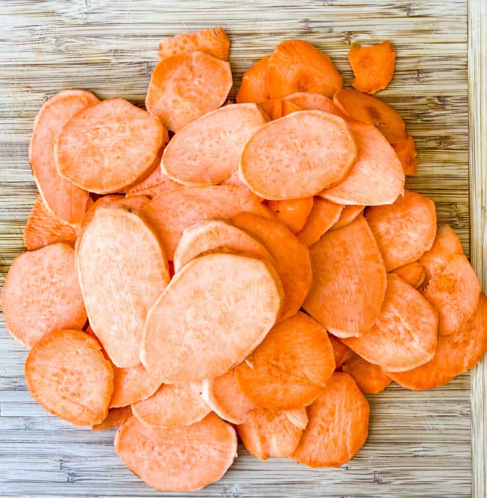 raw sliced sweet potato chips on a cutting board