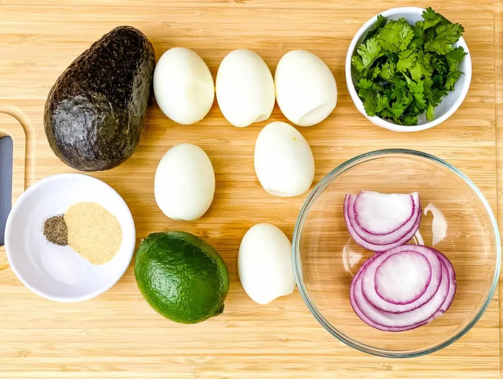 hard boiled eggs, avocado, red onions, and cilantro on a flat surface