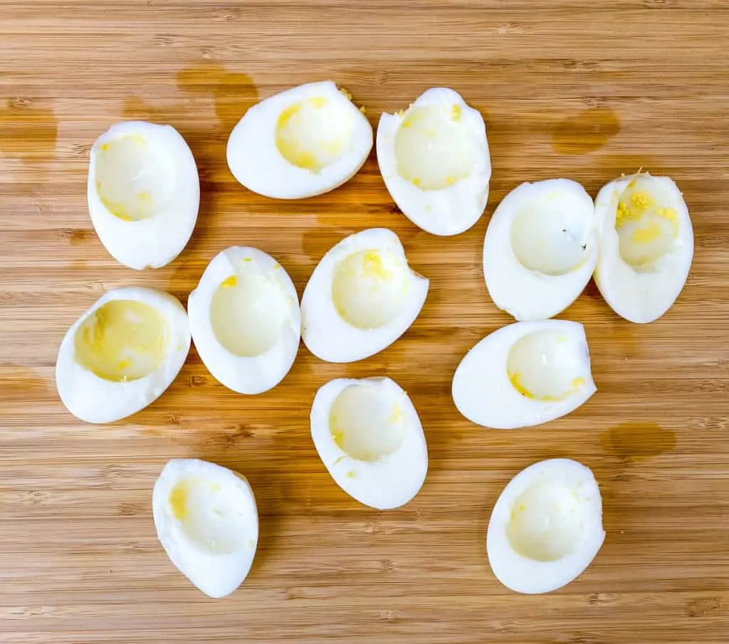 hard boiled eggs cut in half with the yolks removed on a bamboo cutting board