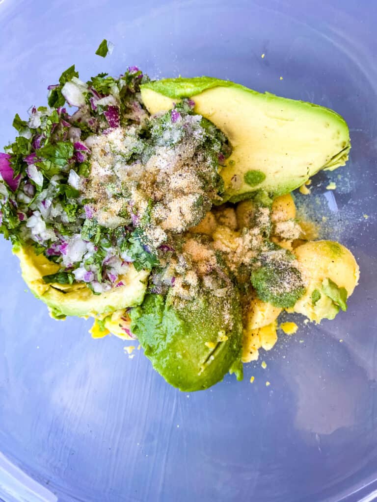 avocado, chopped onions, chopped cilantro, and lime in a glass bowl