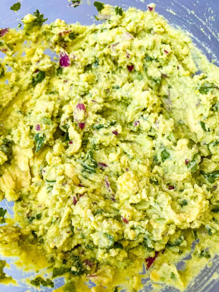 mashed guacamole in a glass bowl