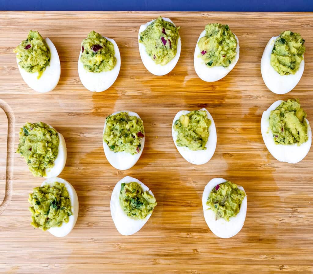 avocado deviled eggs on a bamboo cutting board