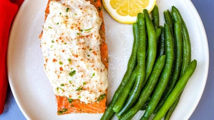 crab stuffed salmon on a plate with green beans and lemon