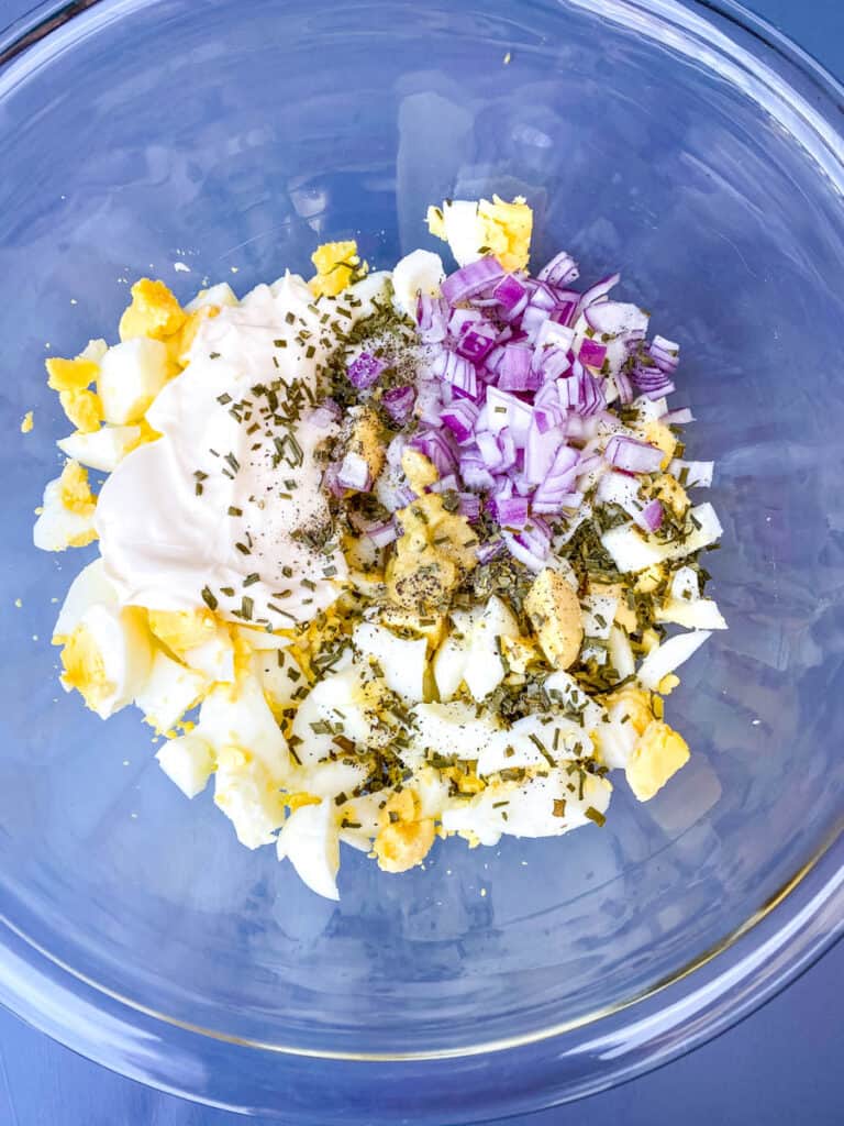 chopped boiled eggs, chopped onions, seasoning, mayo and mustard in a glass bowl