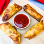 shrimp egg rolls with sweet and sour sauce on a flat surface