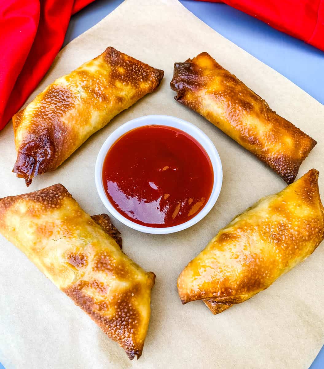 shrimp egg rolls with sweet and sour sauce on a flat surface