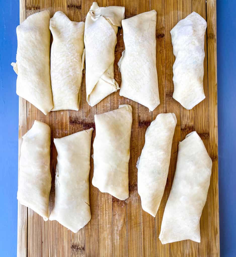 uncooked shrimp egg rolls on a cutting board